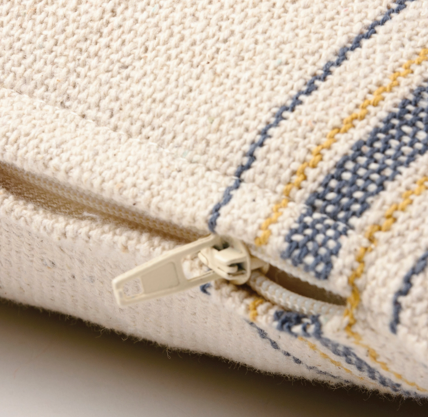 Close-up of a textured fabric pouch with a zipper, featuring blue and yellow stripes.